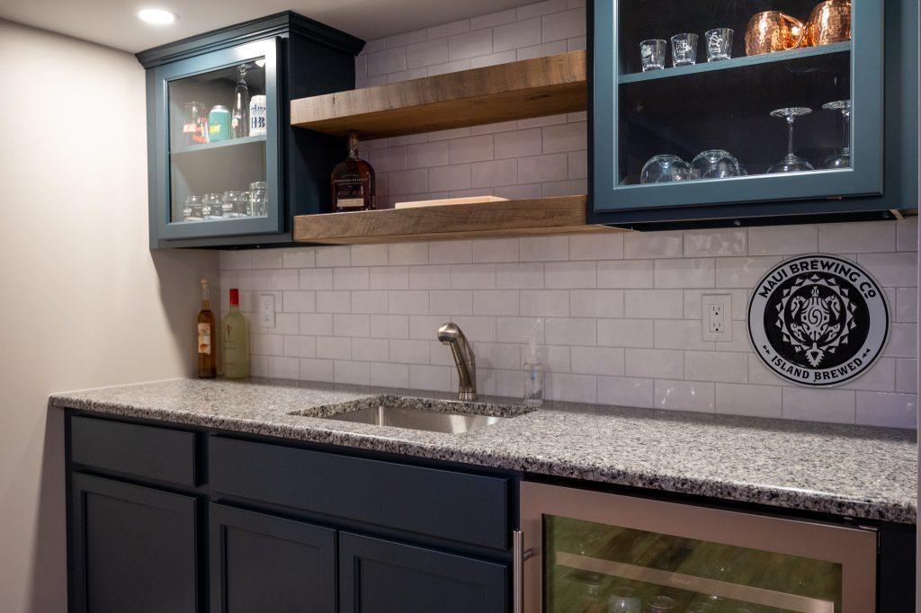 Finished basement wet bar with white backsplash and wood shelving in Oakland Twp., Michigan