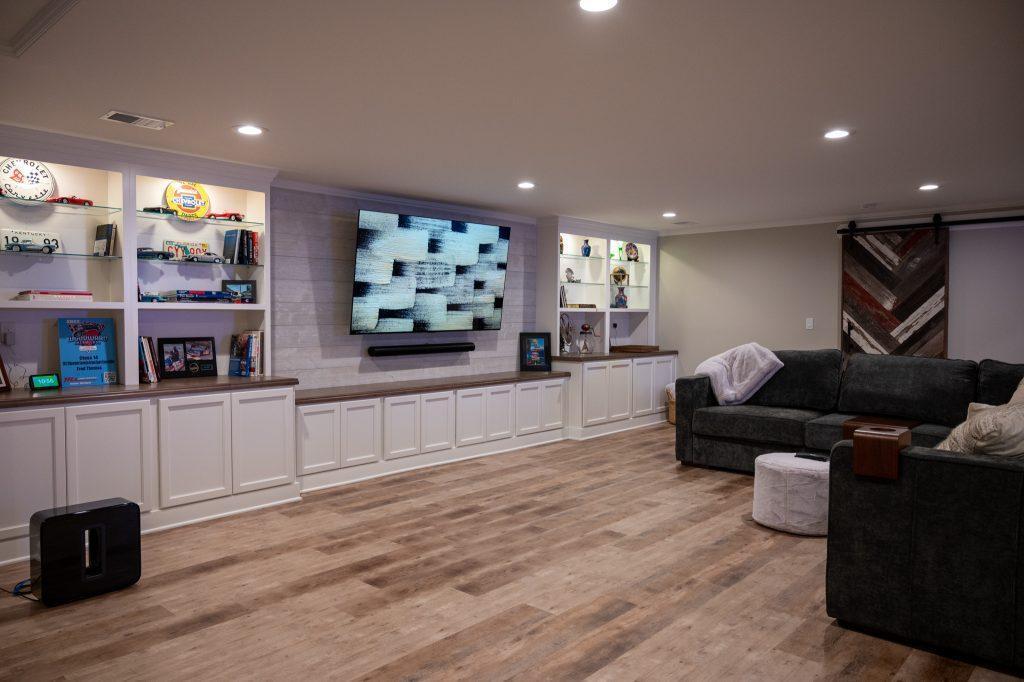 Finished basement living room with white shiplap tv wall and cabinets in Oakland Twp, Michigan