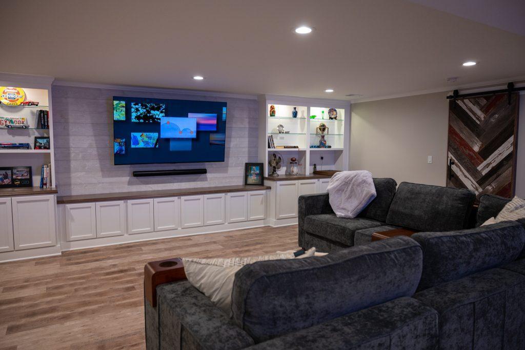 Finished basement living room with white shiplap tv wall and cabinets in Oakland Twp, Michigan