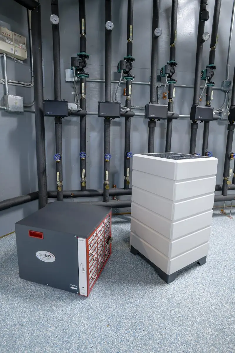 Photo of SaniDRY dehumidifier and Aspen air purifier in basement of home.