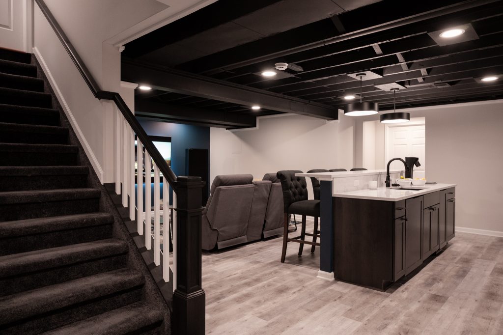 Finished basement in Canton, MI with black ceiling, gray hardwood flooring, kitchenette, and blue backsplash wall