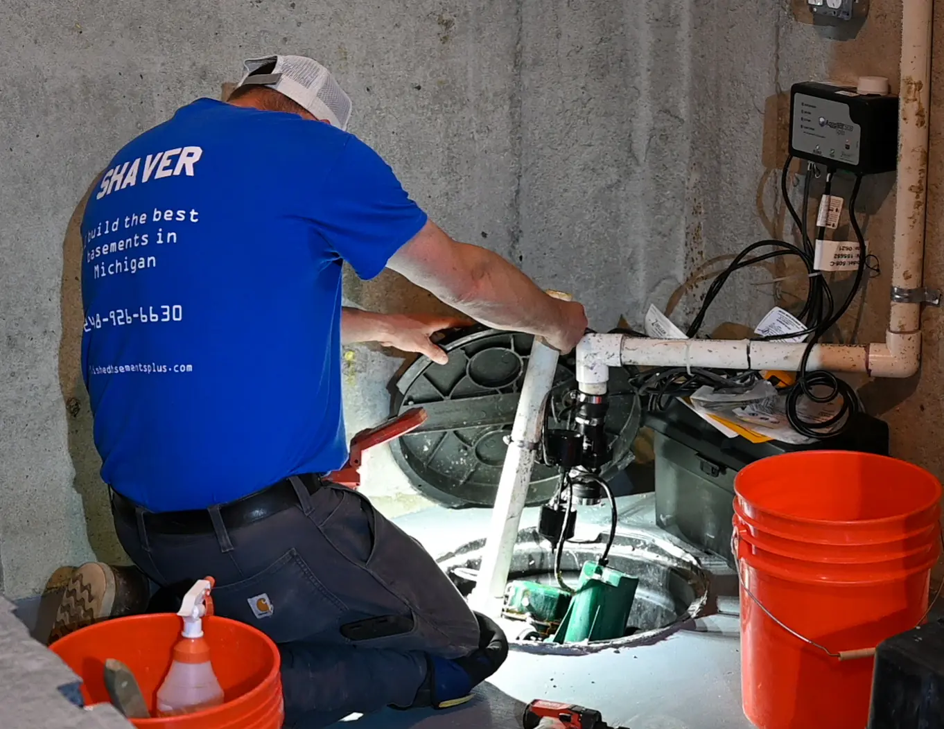 Basements Plus crew member installing a sump pump in a basin.